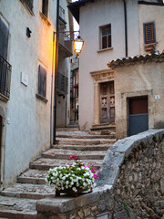 Fancy flower decorated narrow sunny street with stairs in old town in summer sunshine, Italy