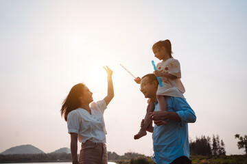 Happy family in the park sunset light. family on weekend running together in the meadow with river Parents hold the child hands.health life insurance plan concept.