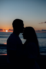 silhouette of couple kissing on the beach at sunset
