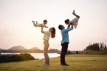 Happy family in the park sunset light. family on weekend playing together in the meadow with river...