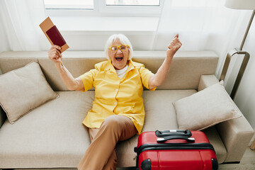 Happy senior woman with passport and travel ticket packed a red suitcase, vacation and health care....