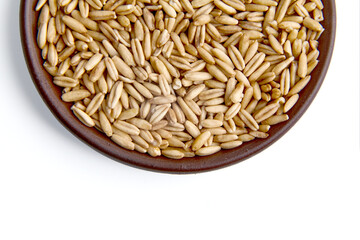 Whole grains of oats in a clay ceramic bowl close-up isolated on white background. Top view with copy space