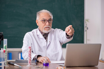 Old male teacher chemist sitting in the classroom