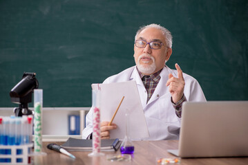 Old male teacher chemist sitting in the classroom