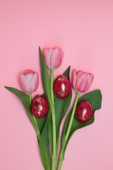 Pink tulips with red gold Easter eggs on a pink background. Easter