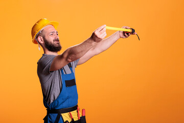 Confident construction worker using tape measure to take measurements and work on refurbishment...
