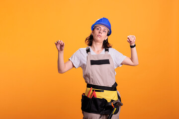 Female construction worker acting dizzy and tired, standing over yellow background and losing...