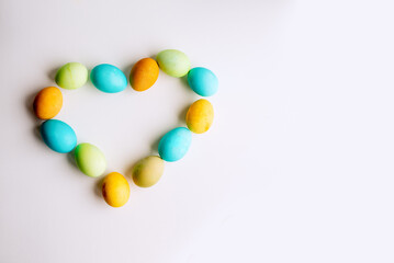 Easter bright, colored eggs in shape of heart lie on isolated white background. Copy space, mock up