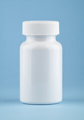 White medical container of pills on light blue background. Drugs and health supplement pills into medicine white bottle health care and medical top view on colored blue background.