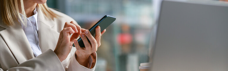 Close up of businesswoman use phone during working on laptop in cafe. Distance work concept