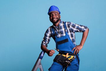 Optimistic builder looking at camera with big smile while resting after finishing work in studio...