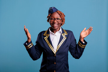 Professional female flight attendant happily greeting arriving passengers at airplane cabin. Woman...