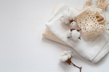 flores de algodón y variedad de telas y encaje en tonos neutros sobre superficie blanca 