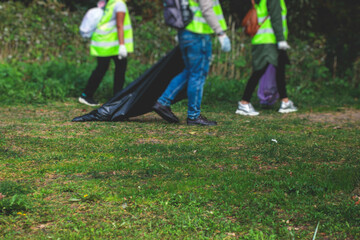 Team group of young people volunteering and participate in community work cleaning day at sandy beach, activists collecting waste, rubbish, garbage and litter in bags in the coast park together