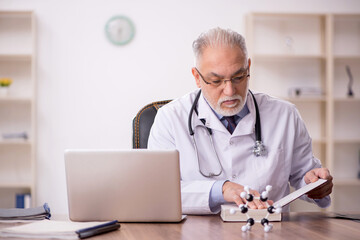 Old male doctor working in the clinic