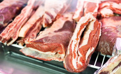 Pieces of various raw beef meat lying on counter of butcher shop. Cuts of fresh ribs, plate and...