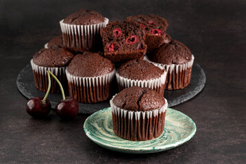 Chocolate muffins with cherries on a dark background.