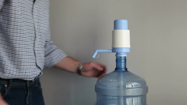 Delivery of clean drinking water to the office and institutions. A man puts bottled artesian water for drinking.