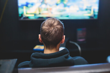 Process of playing video games, video game console with wireless controller, male gamer on a couch with black joystick in front of big wide screen tv © tsuguliev