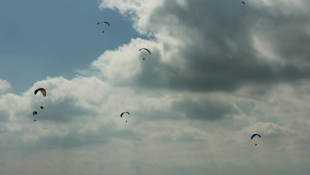 A group of paragliders flying in the sky with clouds. The sport of paragliding gives a feeling of tranquility, peace, strength and freedom in the open air