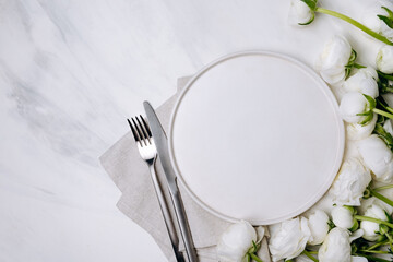 Spring romantic table setting with white plate and white flowers ranunculus. Easter food background. Flat lay.