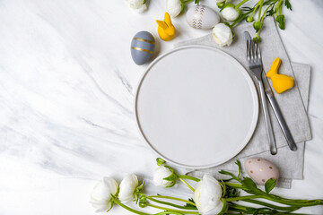 Easter table setting with white plate and decorations, Easter food background. Flat lay.