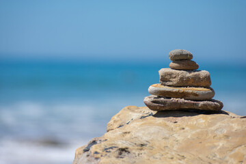 Tower of rocks, stacked with ocean in the background with copy space