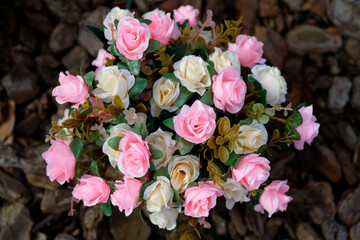 bouquet of artificial pink and beige roses seen from above against dark blurry ground