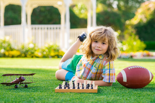 Dream kids and childhood concept. Kid laying on grass enjoy summer lifestyle. Child chessman play chess game, checkmate outdoor.
