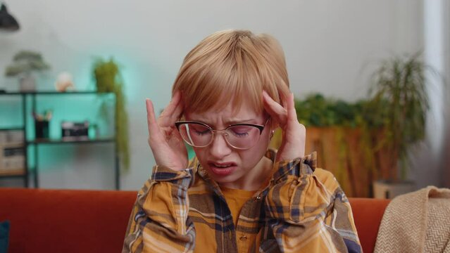 Displeased young woman rubbing temples to cure headache problem, suffering from tension and migraine, stress grimacing in pain high blood pressure at home room apartment. Girl on couch. Lifestyles