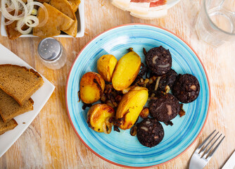 fried black pudding blood sausage with crispy crust,garnished with baked potatoes in their skins,...