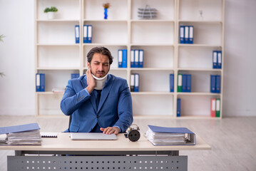 Young male employee after accident sitting at workplace