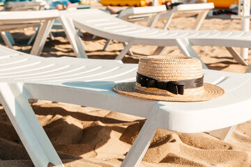 Straw hat on the white deck on the beach. Lounge chair next to a sea. Summer, vacation background	