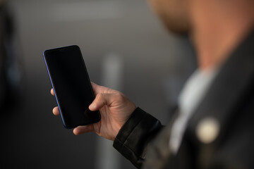 Closeup image of male hands with smartphone, searching internet or social networks, blurred background