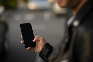 Closeup shot of an man holding mobile phone in hand, blurred background