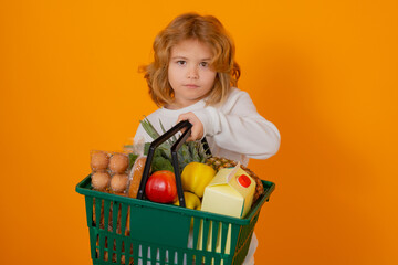 Food store. Child with shopping basket. Studio isolated portrait of cute kid hold shopping cart with grocery.