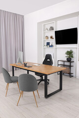 Stylish director's workplace with wooden table, tv zone and comfortable armchairs in office. Interior design