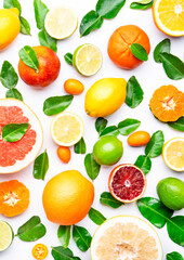 Citrus fruit food background, top view. Mix of different whole and sliced fruits: orange, grapefruit, lime and other with leaves on  white table