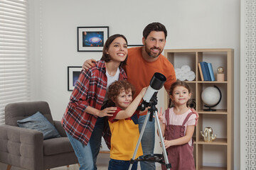 Happy family looking at stars through telescope in room
