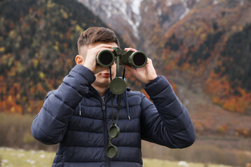 Boy looking through binoculars in beautiful mountains