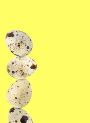 Stacked speckled quail eggs on light yellow background. Space for text