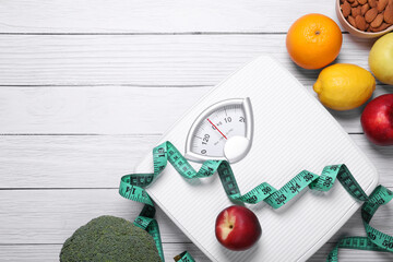 Scales, measuring tape, fresh fruits and almonds on white wooden table, flat lay with space for...