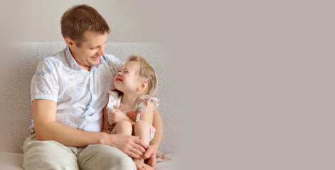 Happy dad and child are sitting on the sofa. The father hugged his little daughter. father's day concept. Everyday moments. Wide banner with copy space.