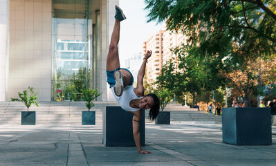 linda mujer morena practicando ejercicios y capoeira en la ciudad sonriendo.