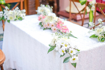 A table with flowers on it and a white tablecloth with pink flowers on it