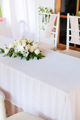 A table with a white tablecloth and a bouquet of white roses on it