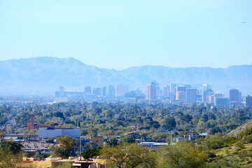 Obraz premium High rise buildings of Phoenix downtown in the Valley of the Sun with a backdrop of South Mountains as seen from North Mountain Park hiking trails on a sunny Spring morning, Arizona