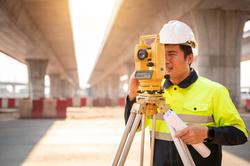 Asian civil engineer or surveyor making measuring under the expressway with theodolite on road...