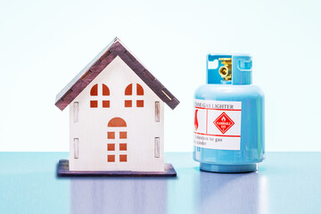  propane tank and model of house on blue background. concept of heating the house.