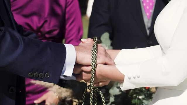 Close up of a married couple handfasting in wedding ceremony act. Slow motion